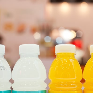 Orange and clear bottles hold ready-to-drink protein powder beverages
