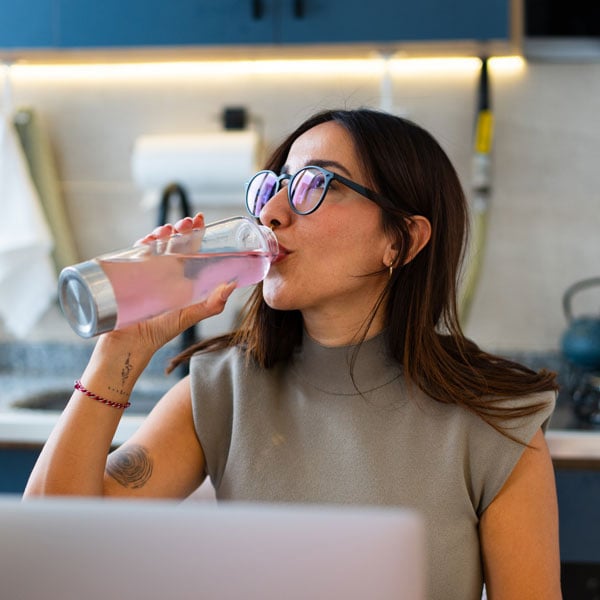 A woman drinking a pink drink with puris clearp in it