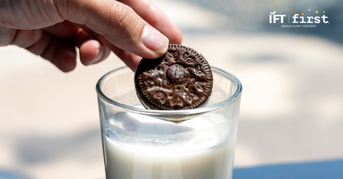 Hand dunks cookie with cream center into glass of milk
